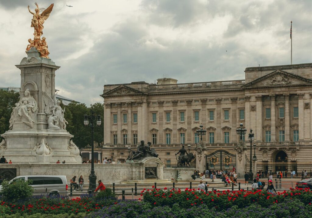 Buckingham palace in the background with the Victoria Memorial and red flowers in bloom in the foreground