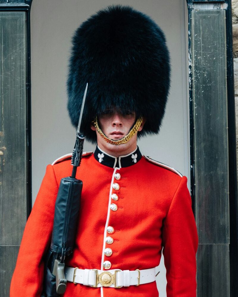 British soldier in red coat and tall hat standing guard in guard box